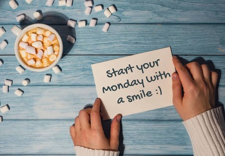 START YOUR MONDAY WITH A SMILE concept text Female hands holding card with white cup of coffee and