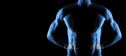 Oklahoma flag on muscled male torso with abs, Oklahoma bodybuilding concept, black background