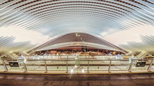 Wide, illuminated station interior at night, characterised by modern structures, Liège-Guillemins