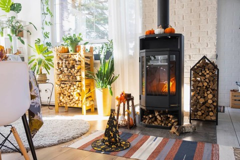 Bright sunny interior of the house with Black Metal Steel fireplace stove with fire and firewood