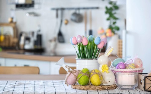 Easter decoration of colorful eggs in a basket and a rabbit on the kitchen table in a rustic style.