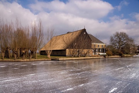 Frozen river the Graafstroom with on the other side a monumental farm in the South Holland village