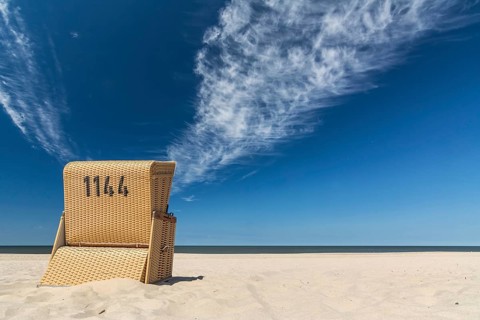 Lonely beach chair near the ocean under blue sky