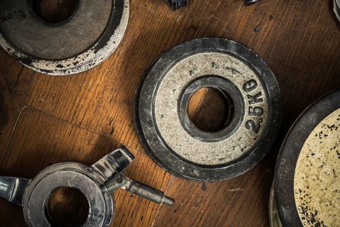 Detail Of Some Vintage Gym Dumbbell Weights Against A Rustic Wooden Floor
