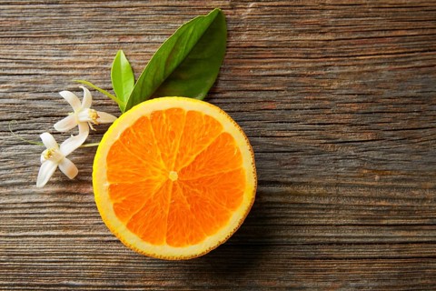 Cut half open orange fruit with orange flower on wooden table