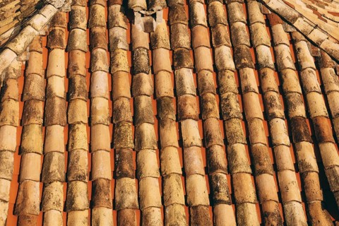 The texture of the old brown shingles on the roof of the building.