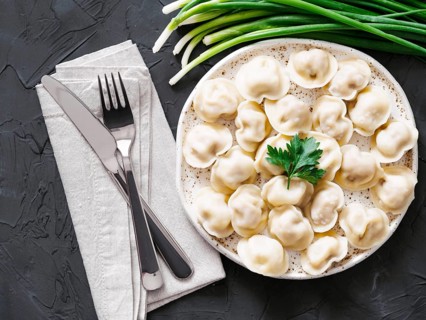 Traditional russian pelmeni, ravioli, dumplings with meat on black concrete background. Top view or
