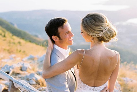 Bride sits on the lap of groom, hugging his shoulders.