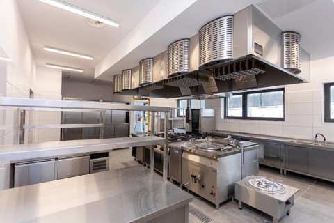 A contemporary commercial kitchen featuring stainless steel appliances and bright, efficient