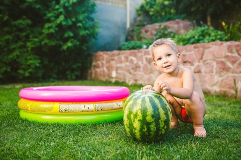 Toddler cute Caucasian white European race boy sitting hugging holding huge watermelon and smiling