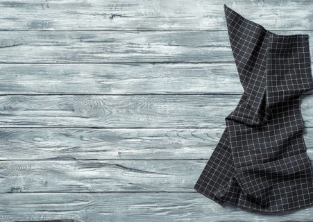 Gray wooden table with balck and white dark linen kitchen towel or textile napkin flat lay. Dark