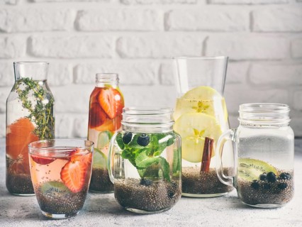 Different chia water in glass on gray background. Chia infused detox water with berries, fruits and