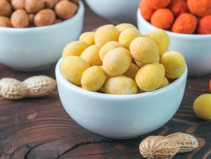 Peanut snack for beer, wine, party bar. Salted peanuts in yellow cheese glaze on brown wooden table