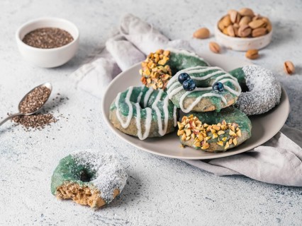 Vegan doughnuts with chia seeds topped with healthy spirulina glaze with pistachio, desiccated