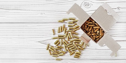 Top down view, carton box with yellow brass ammunition bullets on white wooden desk, banner - space