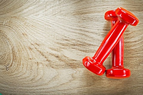 Red dumb-bells on wood board directly above sports training concept