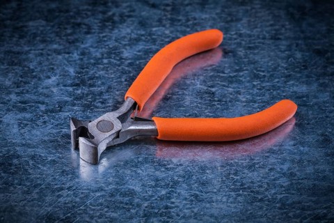 Insulated electric metal nippers on metallic background electricity concept
