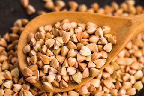 Buckwheat with a spoon on a wooden boards background