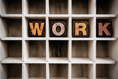 The word WORK written in vintage ink stained wooden letterpress type in a partitioned printer's