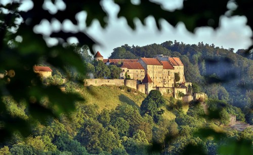Burghausen Castle surrounded by green forests in the evening sun, view from the west, Burghausen,