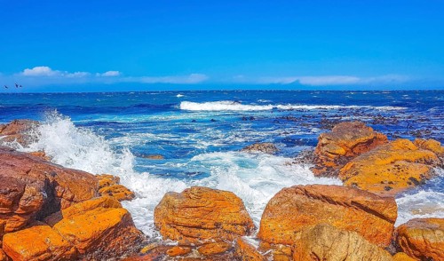 False Bay rough coast landscape with boulders waves and mountains with clouds in Glencairn Simons