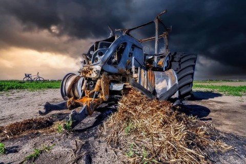 Fully destroyed burnt down tractor on a field