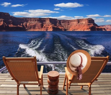 Waves from the boat cut through the Lake Powell. At the stern of the vessel are two deck chairs. On