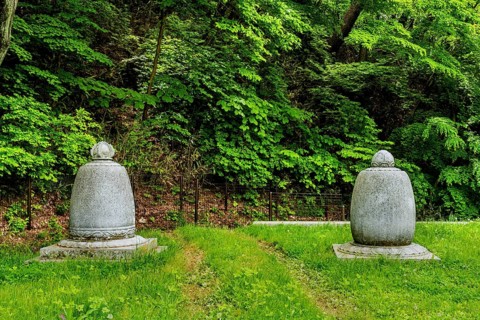Haeinsa-gil, South Korea. May 26, 2020: Two Buddhist urns on lush lawn in front of mountain forest