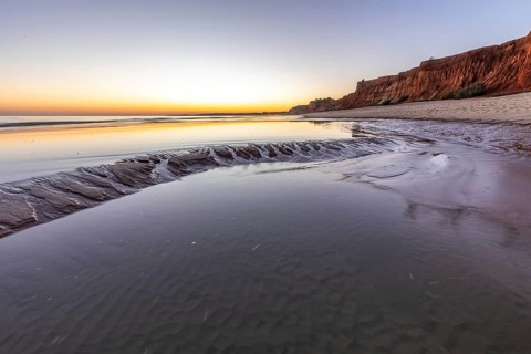 Sea with reflection at low tide in the calm waters of the Atlantic. Landscape shot of the sunset on
