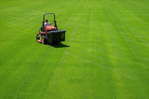 Mowing grass at the football stadium in Lubin, Poland, Europe