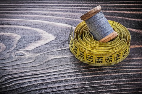 Vintage spool of thread tape measure on wooden board handicraft concept