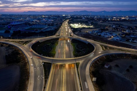 Aerial drone top view of a modern motorway junction roundabout with cars moving fast.