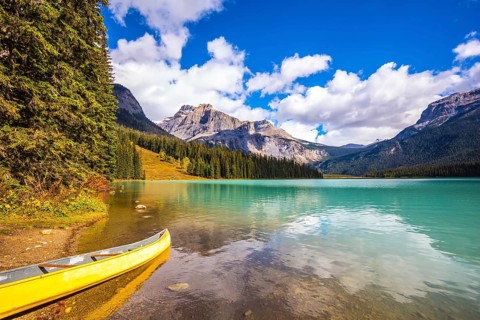 Sunny day in autumn Yoho National Park. In shallow water, the boat is moored. The concept of