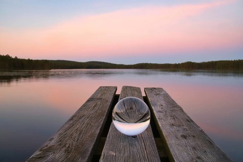 Glass ball on a wooden pier at a Swedish lake at evening hour. Nature shot from Scandinavia