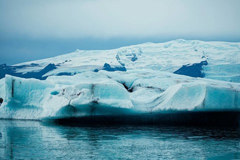 Vast iceberg floating near a glacier under gray skies, iceberg, glacier, snow, ice rock, ice