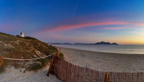 Picturesque Playa del Muro beach with sand dunes and a view of the historic maritime observation