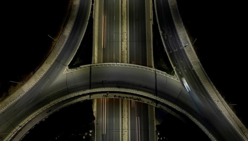 Aerial drone top view of a modern motorway junction roundabout with cars moving fast.