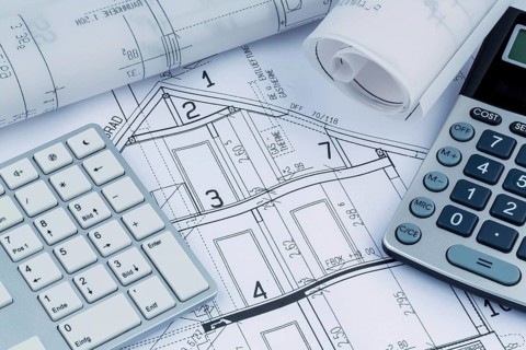An architect's construction plan with a calculator. Symbolic photo for financing and planning a new