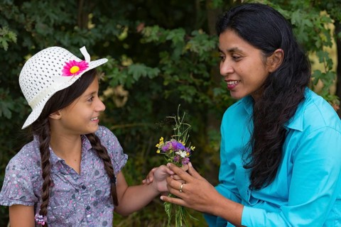 Girl gives mum a bouquet of flowers she picked herself