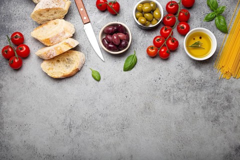 Food composition with sliced ciabatta, olives, olive oil, spaghetti, fresh basil, cherry tomatoes
