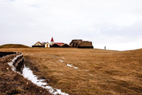 An expansive landscape with a church and traditional buildings in the background, Iceland, Europe