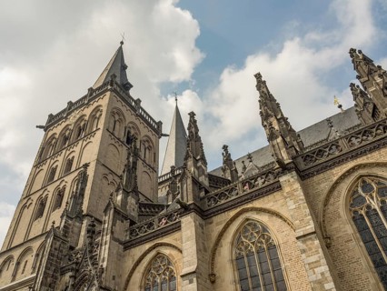 Impressive Gothic building with high towers and detailed decorations under a slightly cloudy sky,