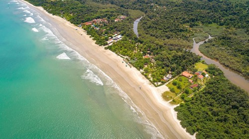 Close-up aerial view of a Green Coast beach with turquoise water, meandering river and forest,