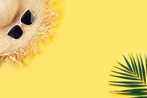 Vacation travel planning simple theme of straw hat sunglasses and palm leaves on uniform yellow