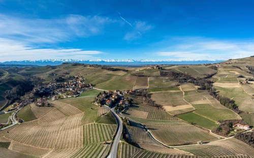 The hilly countryside in the Italian Piedmont with the village of Barolo and snow-covered mountains