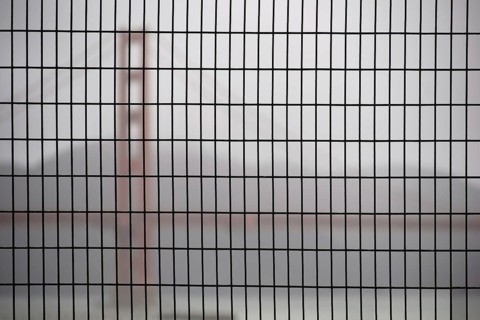 The Golden Gate Bridge blurred behind a fence in hazy rainy weather