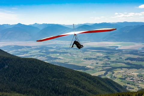 Long shot of flying extremal hang glider. Young man enjoying his recreational journey to Creston,