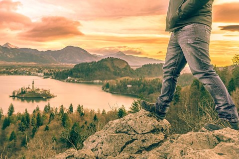 Man equipped with hiking shoes climbed on rocks above the lake Bled from Slovenia, in a December