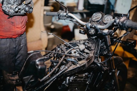 Mechanic repairing motorcycle in a workshop, focusing on engine and gauges