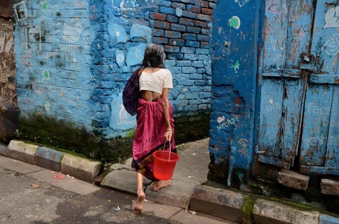 Woman with bucket walking in narrow lane, Kolkata, West Bengal, India, Asia